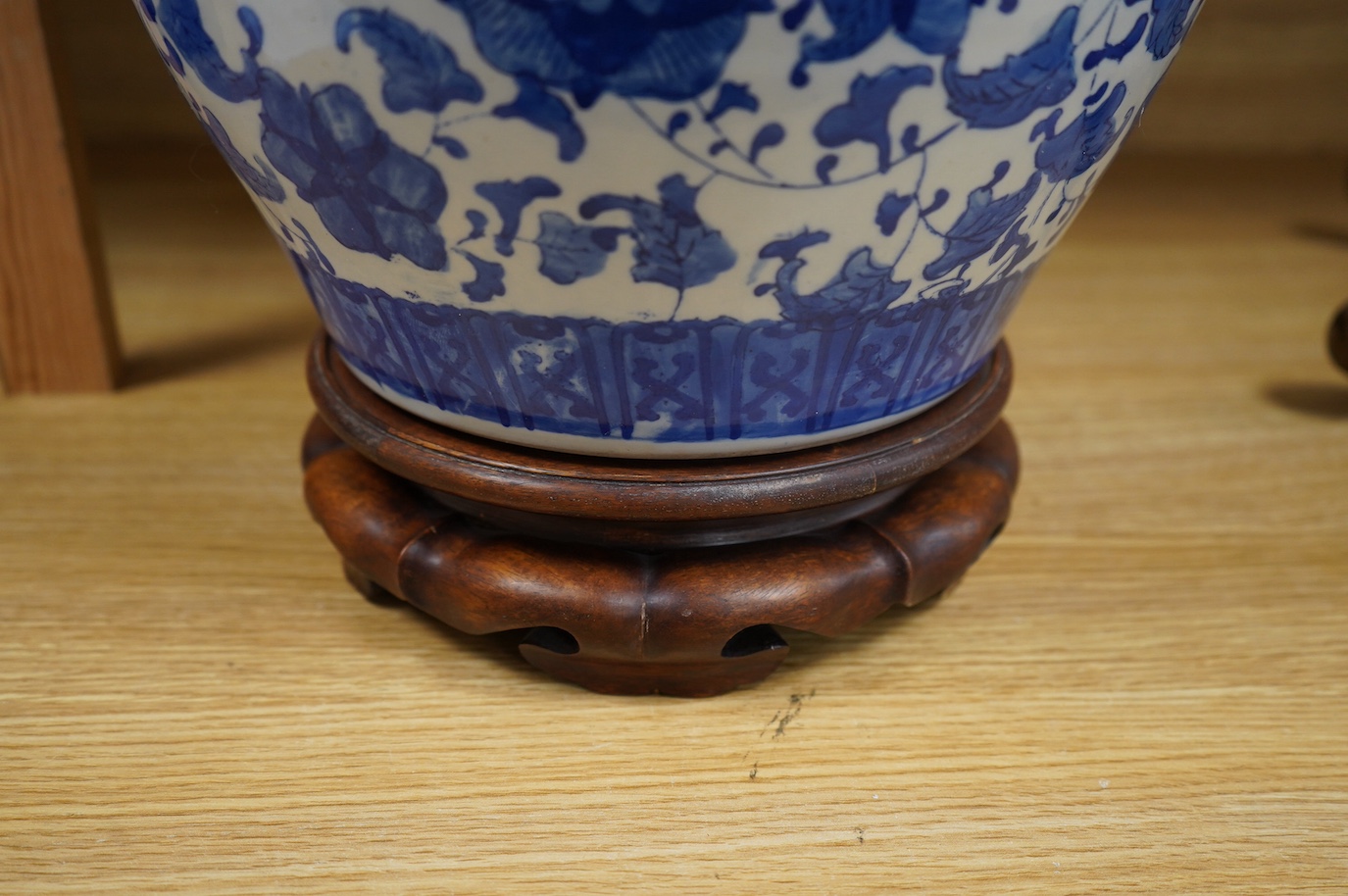 A Chinese blue and white floral jardiniere on hardwood stand, overall 32cm high. Condition - good